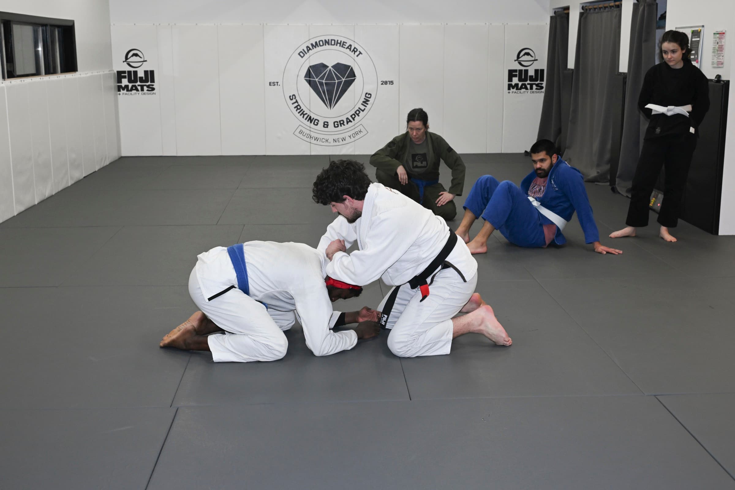 BJJ gi rolling at Diamondheart Brooklyn with logo wall